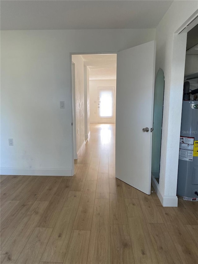 hallway featuring electric water heater and light wood-type flooring