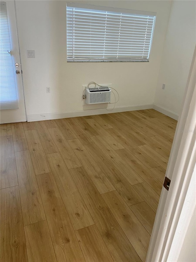 unfurnished room featuring light wood-type flooring and a wall mounted air conditioner