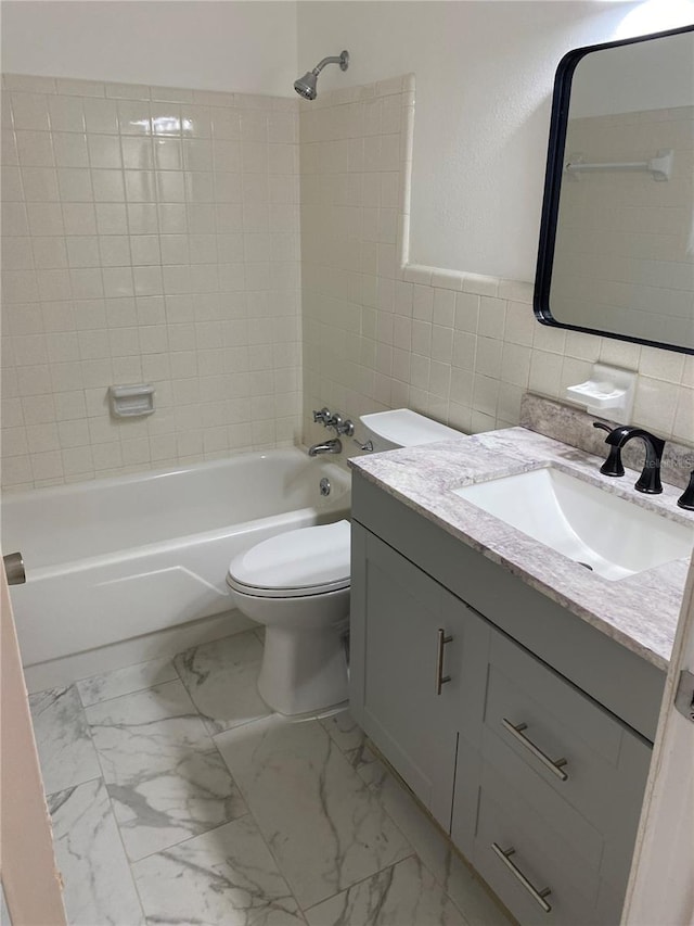 full bathroom with tile walls, toilet, vanity, and tiled shower / bath