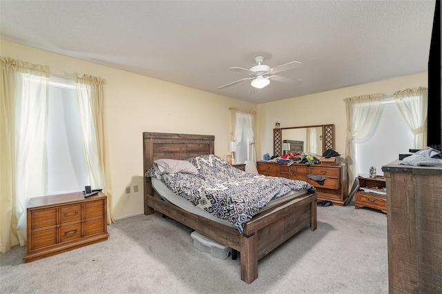 bedroom with ceiling fan, a textured ceiling, and light carpet