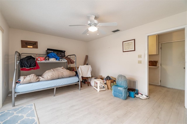 bedroom featuring ceiling fan, light hardwood / wood-style floors, and a textured ceiling