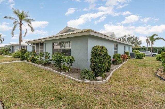 view of property exterior with a lawn, cooling unit, and stucco siding