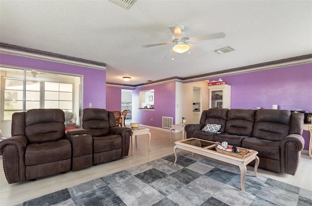 living room featuring a textured ceiling, ornamental molding, and visible vents