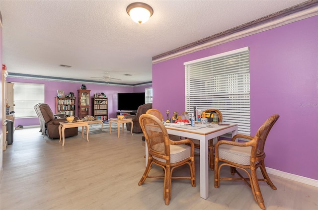 dining area featuring light wood-style floors, ceiling fan, a textured ceiling, and crown molding