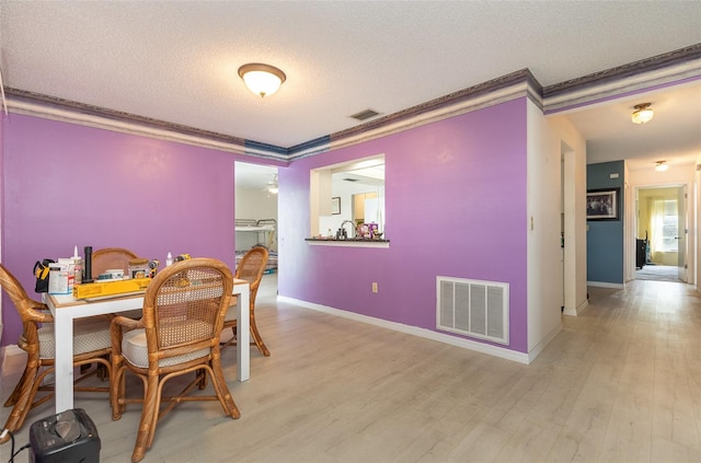 dining space with visible vents, a textured ceiling, and ornamental molding