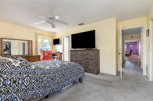 carpeted bedroom featuring a textured ceiling, visible vents, and a ceiling fan