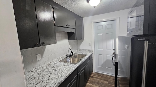 kitchen with sink, a textured ceiling, stainless steel fridge, dark hardwood / wood-style flooring, and decorative backsplash