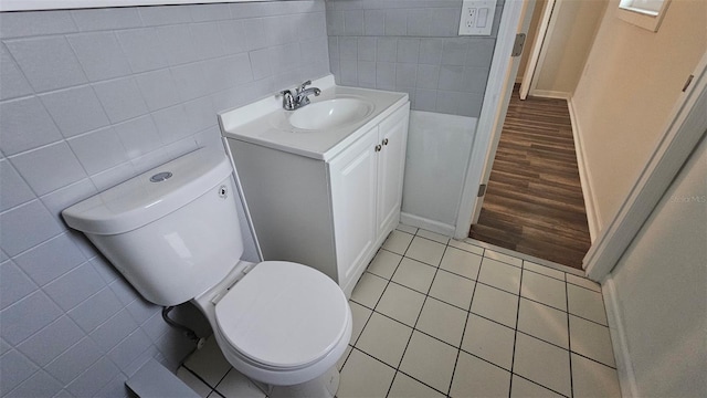 bathroom with tile patterned flooring, vanity, tile walls, and toilet