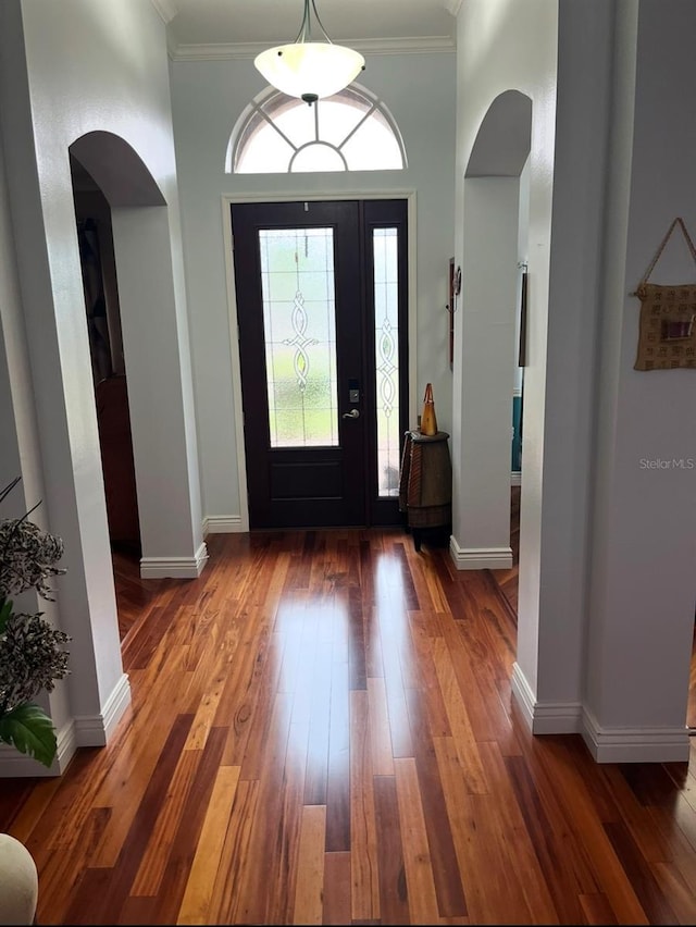 entryway with ornamental molding and dark hardwood / wood-style floors