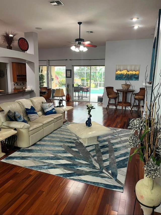 living room with dark wood-type flooring and ceiling fan