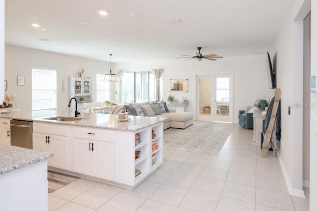 kitchen with pendant lighting, sink, white cabinetry, light stone countertops, and a healthy amount of sunlight