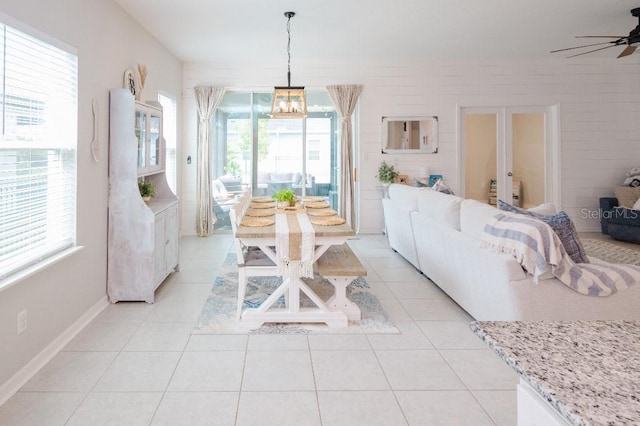 tiled living room with ceiling fan with notable chandelier and plenty of natural light