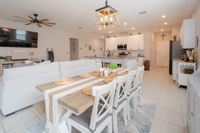 dining room with ceiling fan with notable chandelier and light tile patterned floors