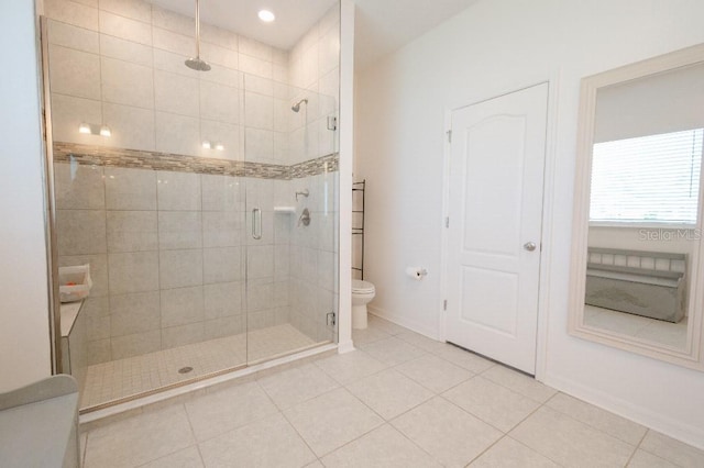 bathroom featuring tile patterned floors, toilet, and a shower with door