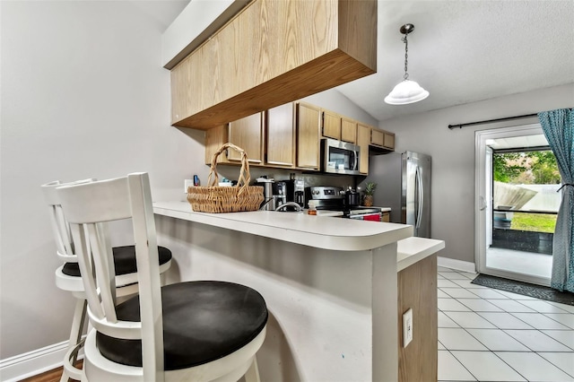 kitchen featuring lofted ceiling, stainless steel appliances, hanging light fixtures, kitchen peninsula, and light tile patterned floors