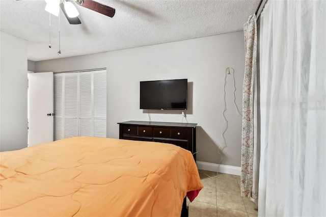 tiled bedroom with a textured ceiling, a closet, and ceiling fan