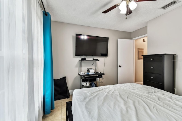 tiled bedroom featuring ceiling fan and a textured ceiling