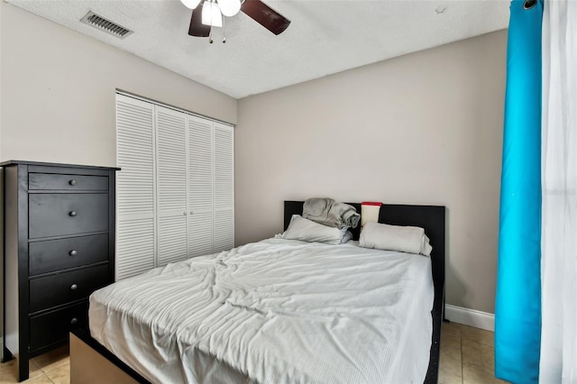 bedroom with ceiling fan, light tile patterned floors, and a closet