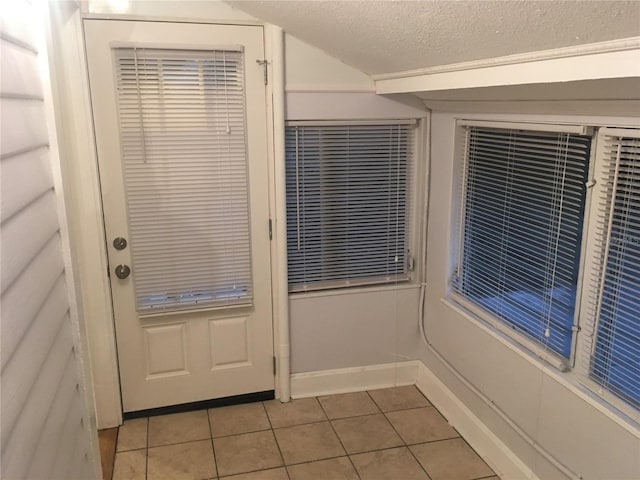 doorway featuring light tile patterned floors and a textured ceiling