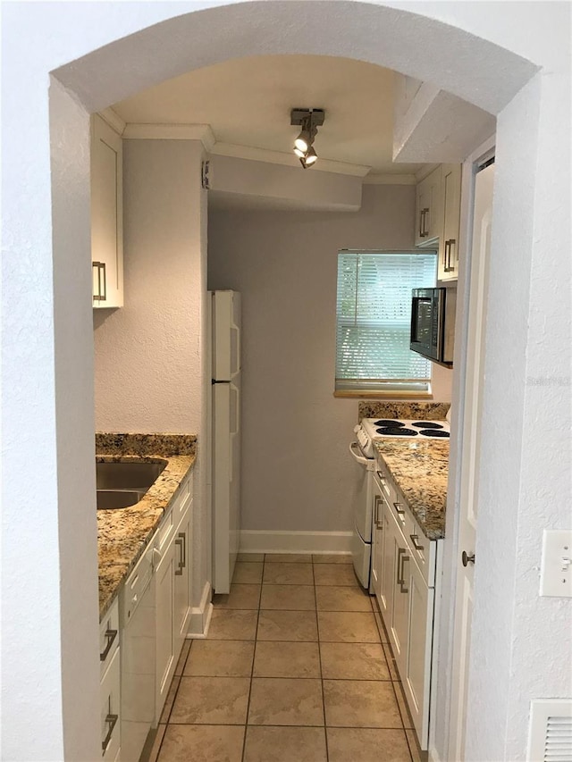 kitchen with light stone countertops, sink, white cabinets, and white appliances