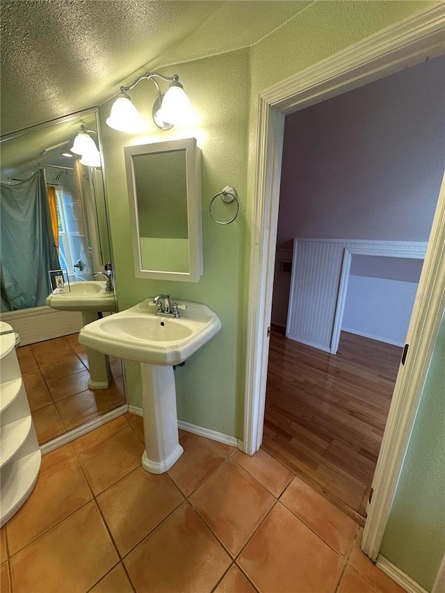 bathroom with tile patterned floors, double sink, and a textured ceiling