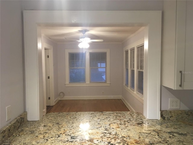 unfurnished dining area featuring ceiling fan, ornamental molding, and dark hardwood / wood-style flooring