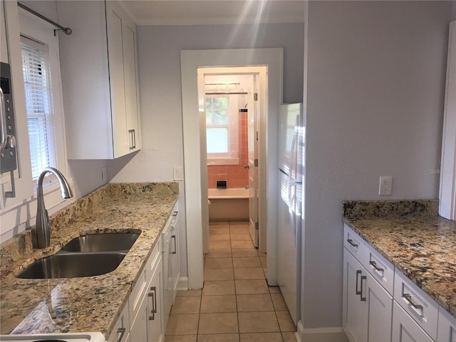 kitchen featuring sink, light stone counters, light tile patterned floors, white appliances, and white cabinets