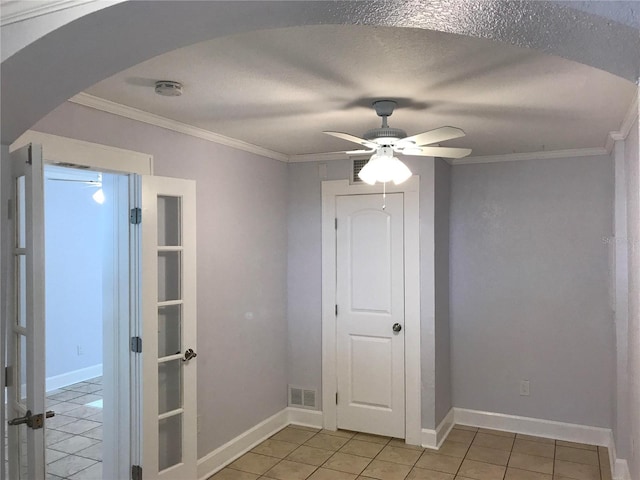 tiled spare room with a textured ceiling, ornamental molding, and ceiling fan