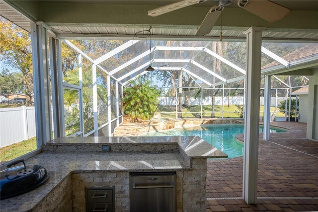 view of swimming pool featuring an outdoor kitchen, a patio area, glass enclosure, and a bar