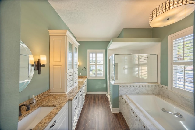 bathroom featuring plus walk in shower, wood-type flooring, vanity, and a textured ceiling