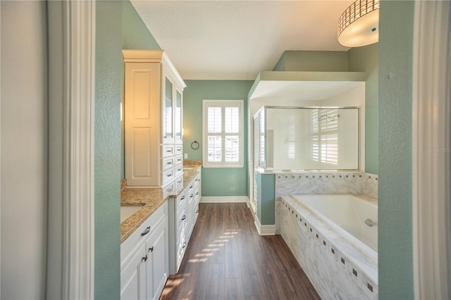 bathroom with plus walk in shower, wood-type flooring, vanity, and a textured ceiling