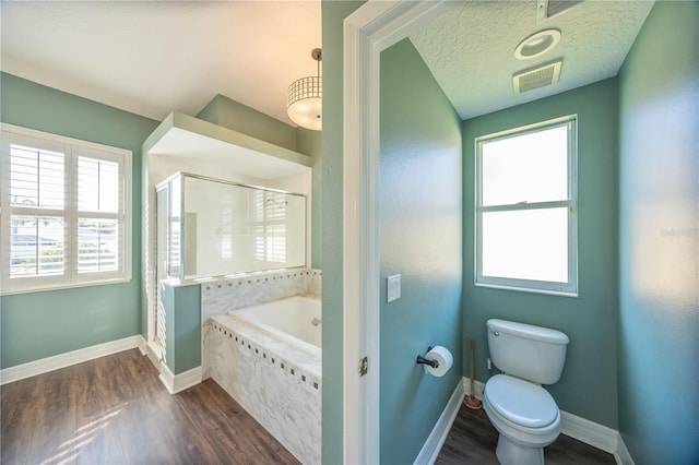 bathroom featuring independent shower and bath, a healthy amount of sunlight, a textured ceiling, and toilet