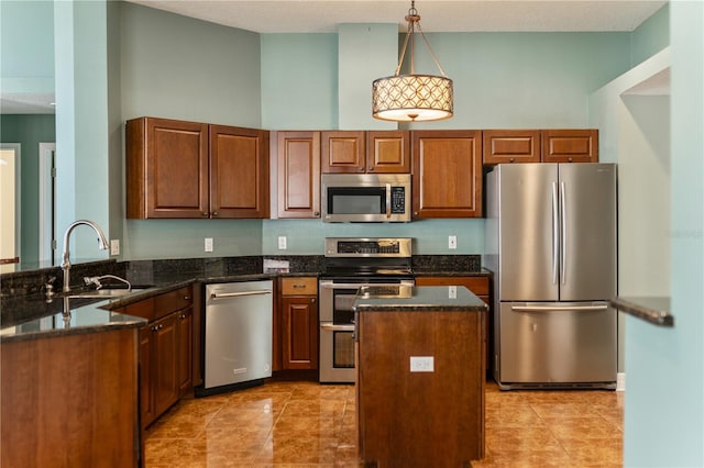 kitchen with decorative light fixtures, sink, dark stone countertops, a center island, and stainless steel appliances