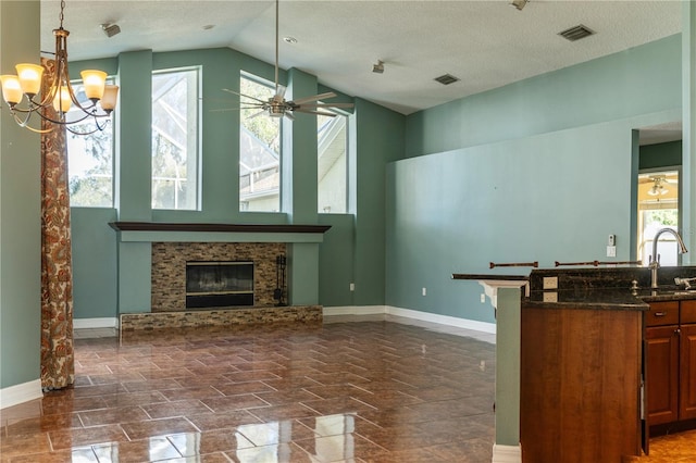 living room with ceiling fan with notable chandelier, a wealth of natural light, a textured ceiling, and vaulted ceiling