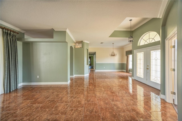 foyer entrance featuring french doors, ornamental molding, and a textured ceiling