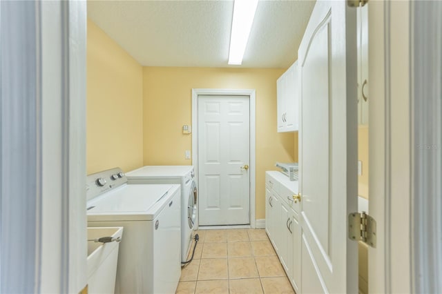 laundry area featuring sink, cabinets, a textured ceiling, light tile patterned floors, and washer and clothes dryer