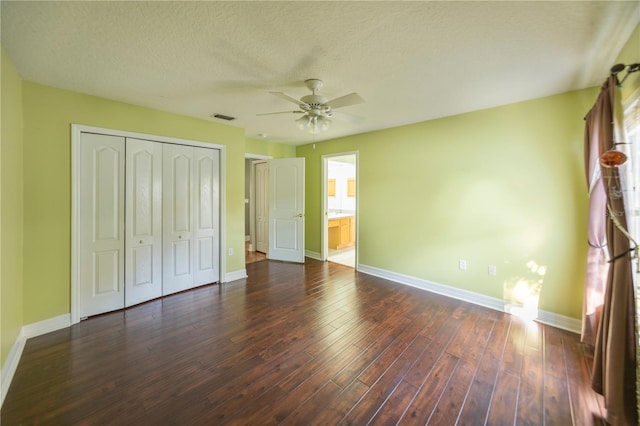 unfurnished bedroom with dark wood-type flooring, ceiling fan, multiple windows, ensuite bathroom, and a textured ceiling