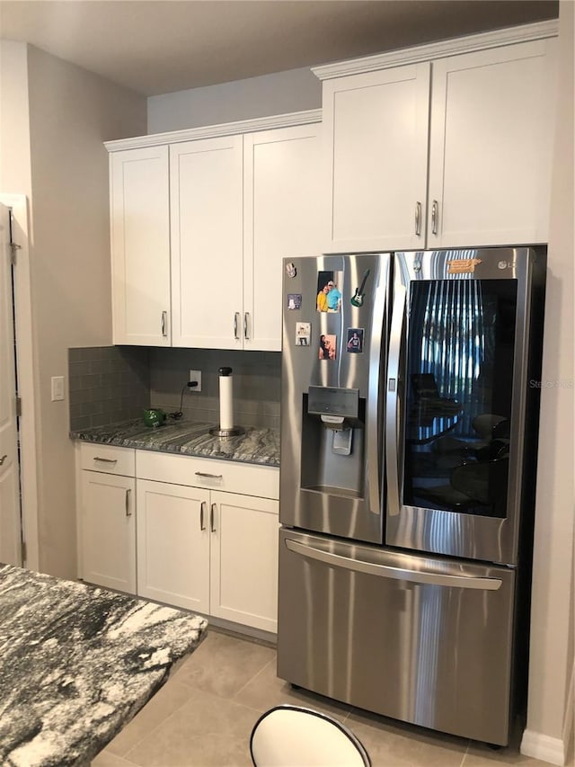 kitchen with stainless steel fridge with ice dispenser, dark stone countertops, and white cabinetry