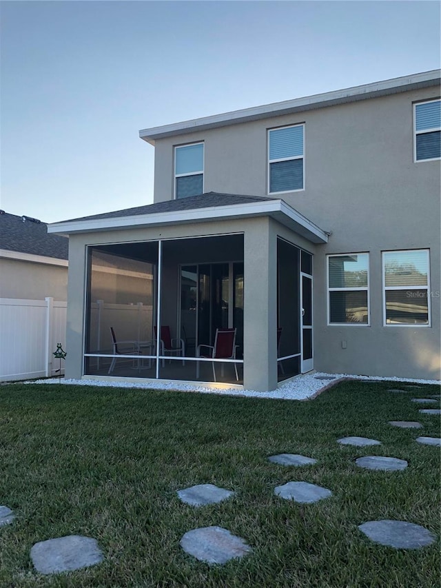 back of property with a yard and a sunroom