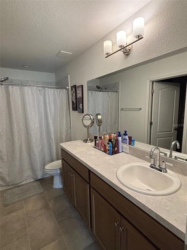 bathroom with tile patterned floors, a textured ceiling, toilet, and vanity