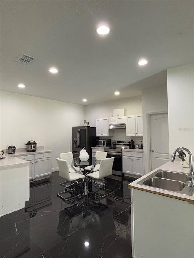 kitchen with sink, white cabinetry, dark tile patterned floors, and appliances with stainless steel finishes