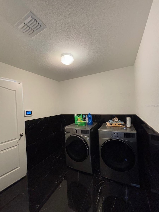 clothes washing area with a textured ceiling and washing machine and clothes dryer