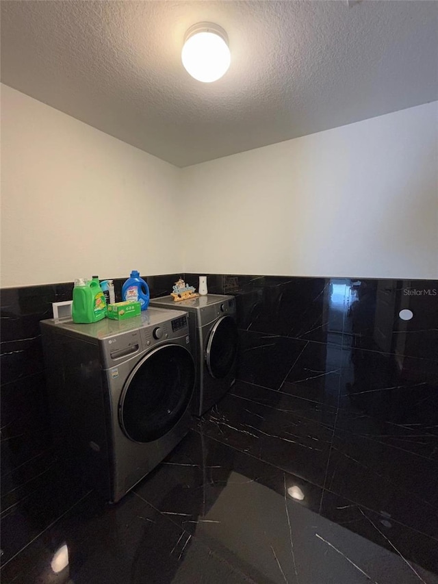 laundry room with a textured ceiling and washer and clothes dryer