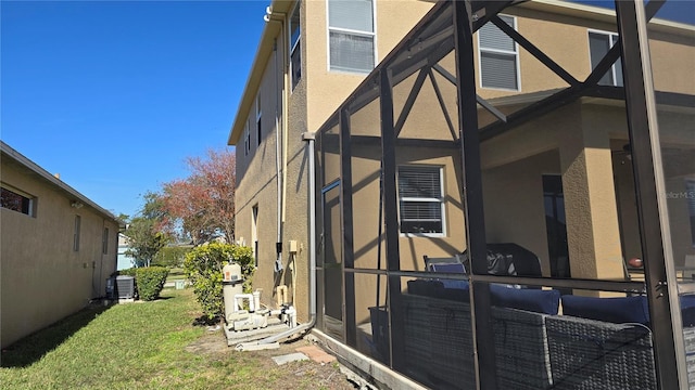 view of side of property featuring central AC unit and a lawn