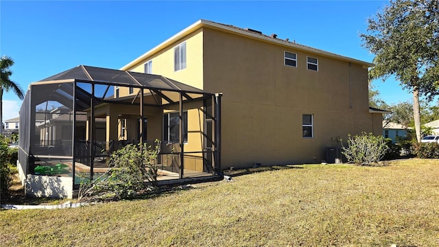 rear view of property with glass enclosure and a lawn