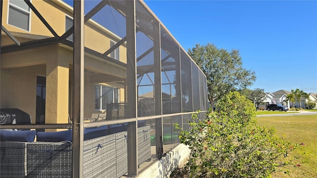 view of property exterior with glass enclosure and a lawn