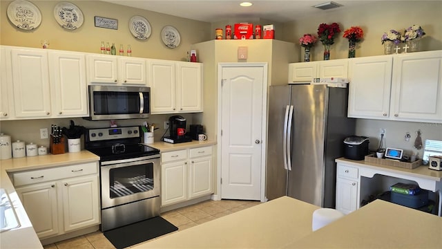 kitchen with stainless steel appliances, white cabinetry, and light tile patterned floors