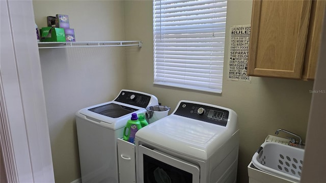 clothes washing area featuring cabinets, washer and dryer, and sink