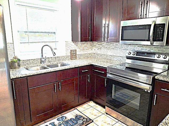 kitchen with light stone counters, sink, tasteful backsplash, and stainless steel appliances