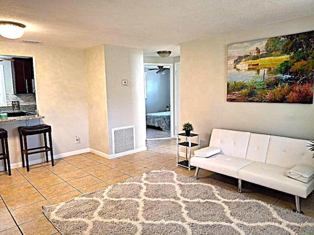 living room with light tile patterned floors, a textured ceiling, and ceiling fan